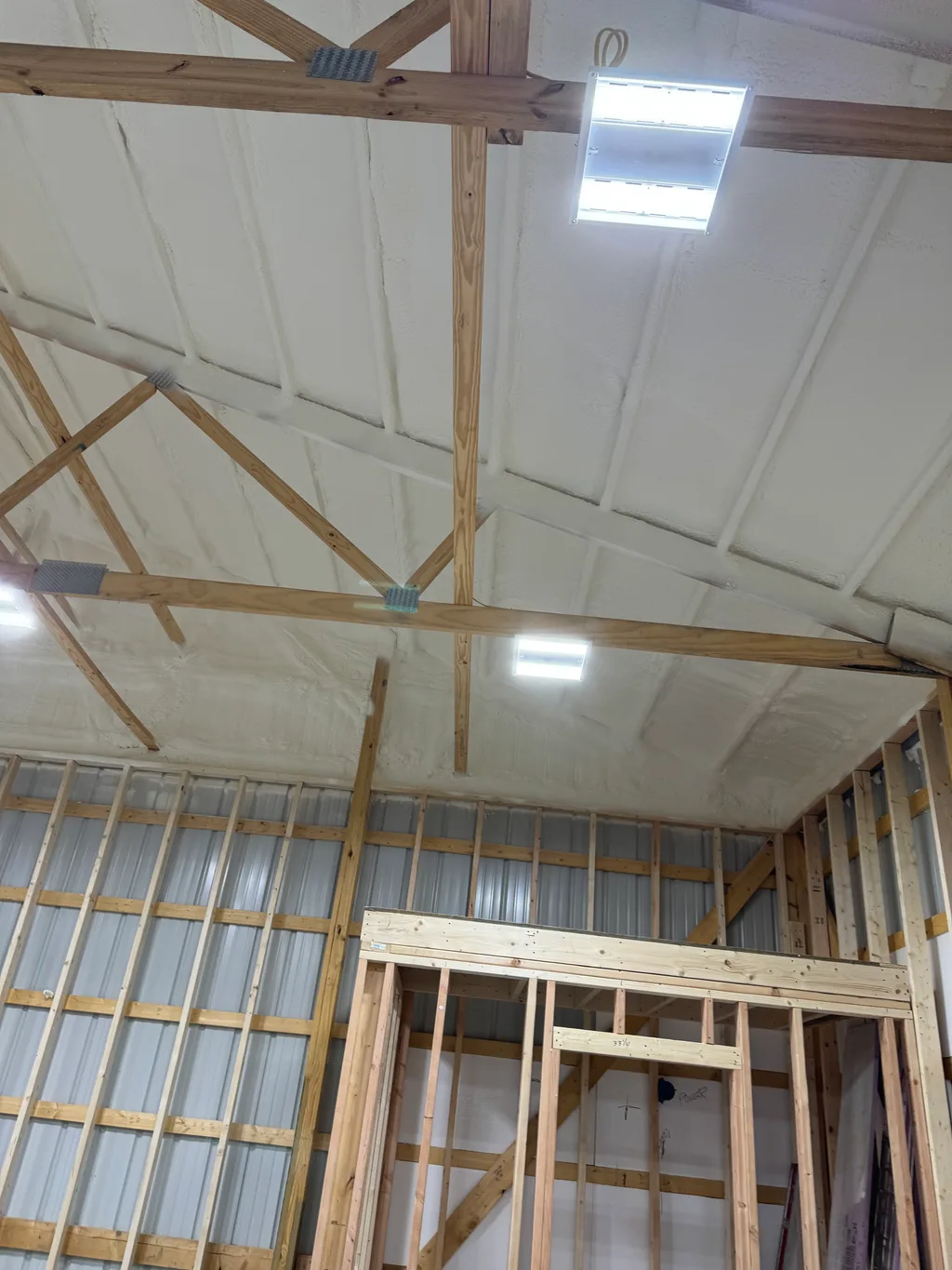 Foamed barn ceiling above a newly framed doorway opening and steel wall panels