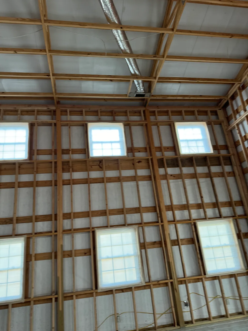 Bare timber framing across steel walls with six windows and a duct near the roof