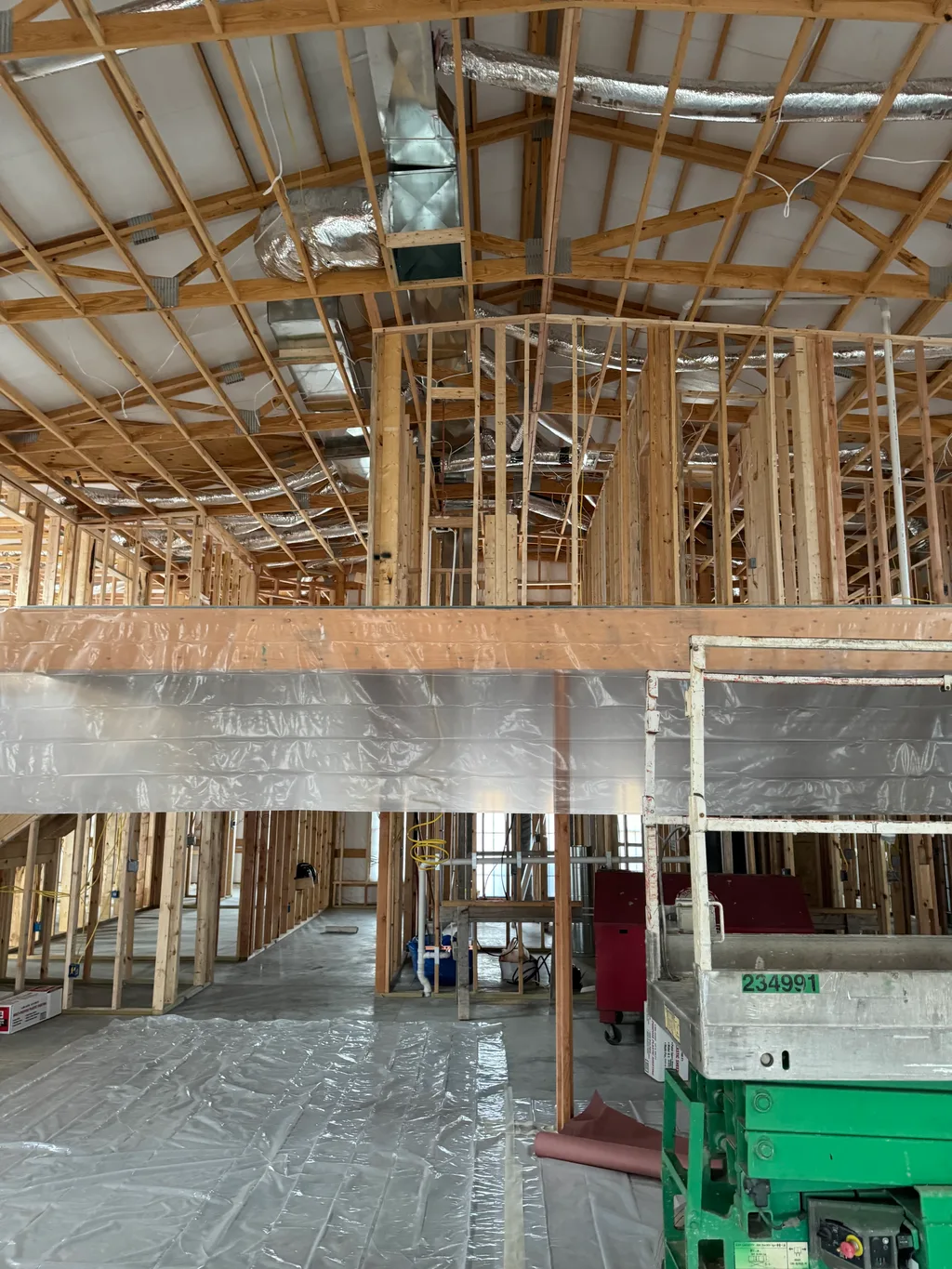 Foil ducting and plastic sheeting above a covered floor with a green lift alongside
