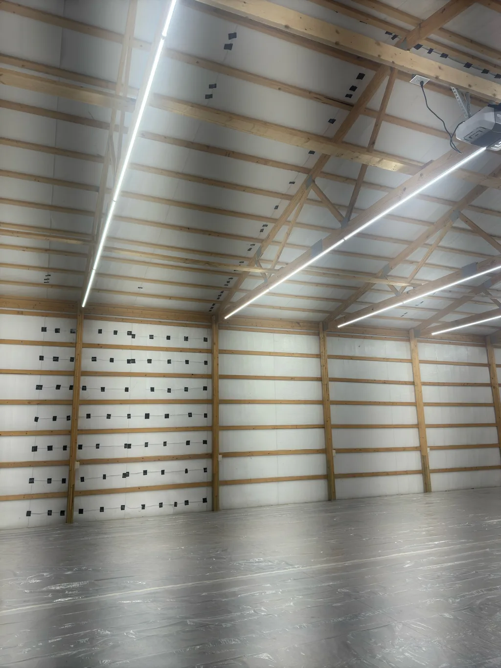 White lined barn walls and ceiling with dark clips, lit by long strip lights