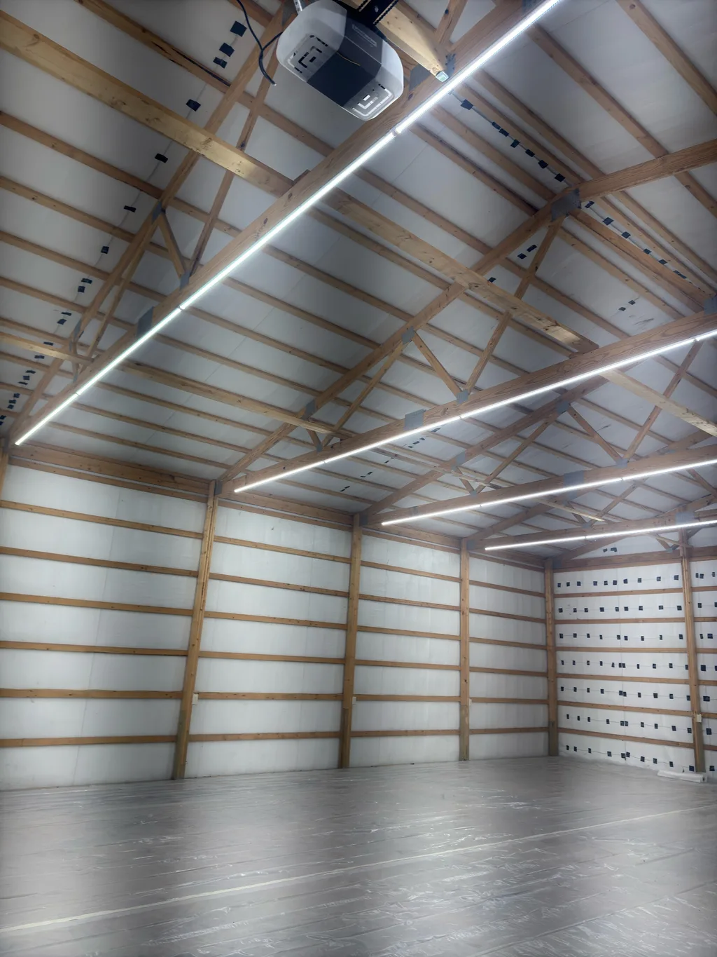 Lined barn ceiling and walls with a door opener motor mounted on the timber above