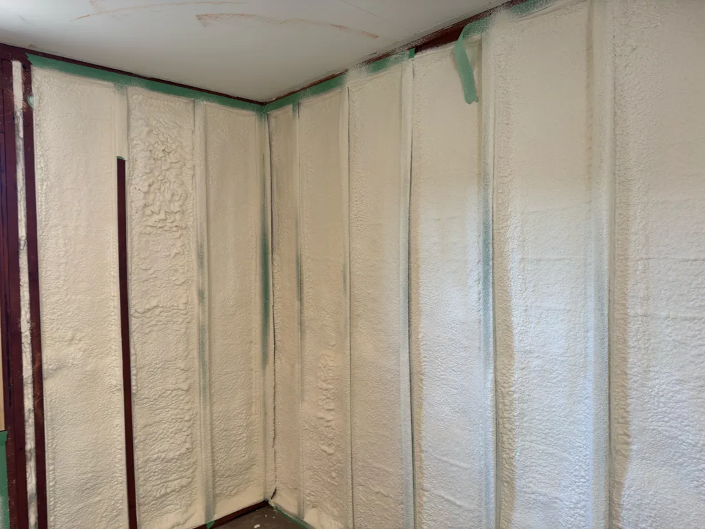 Smooth foamed walls meeting at a corner with green tape along the trim lines