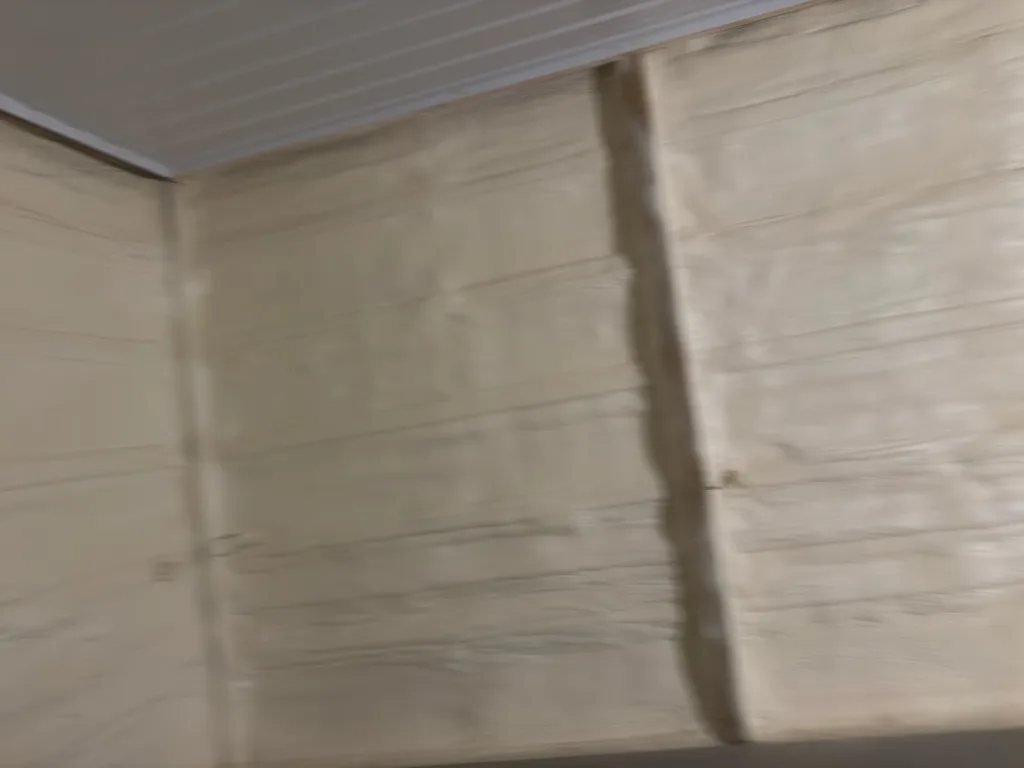 Smooth cream foam covering two walls of an empty room below a white metal ceiling