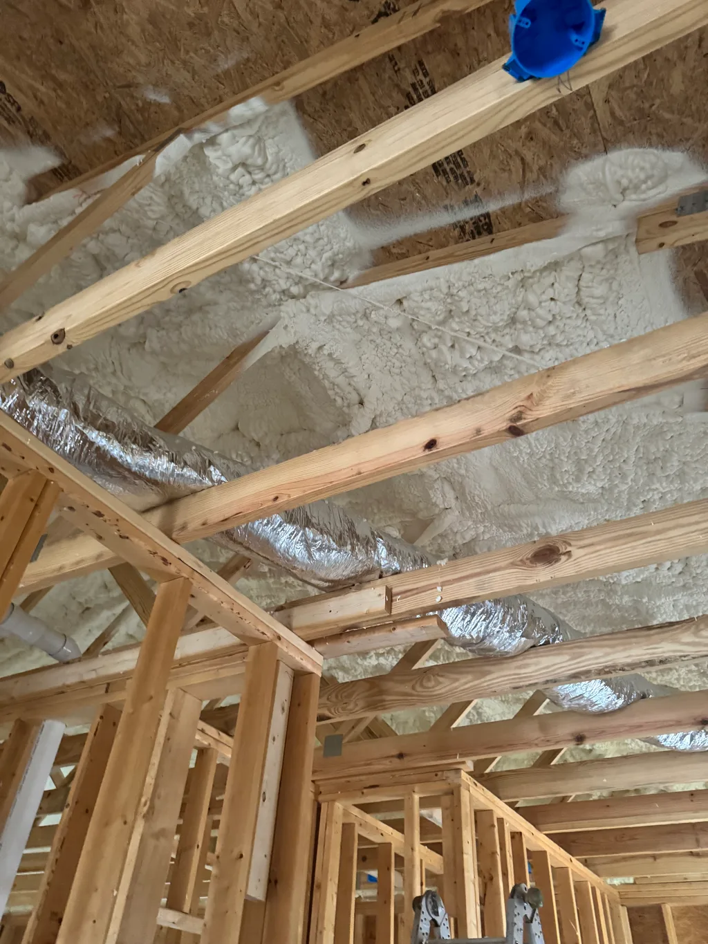 Foamed roof deck above new timber framing with a foil duct and blue outlet box